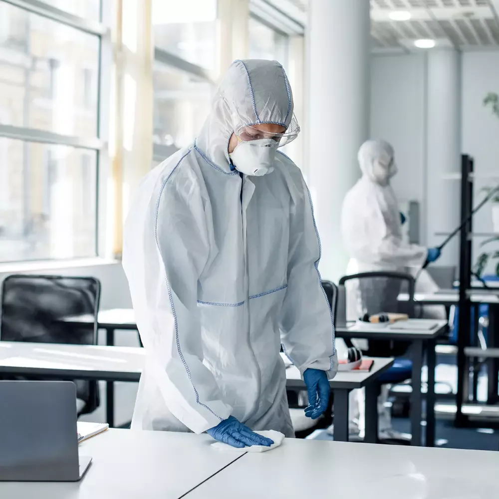 Flächendesinfektion mit Schutzausrüstung in einem Büro
