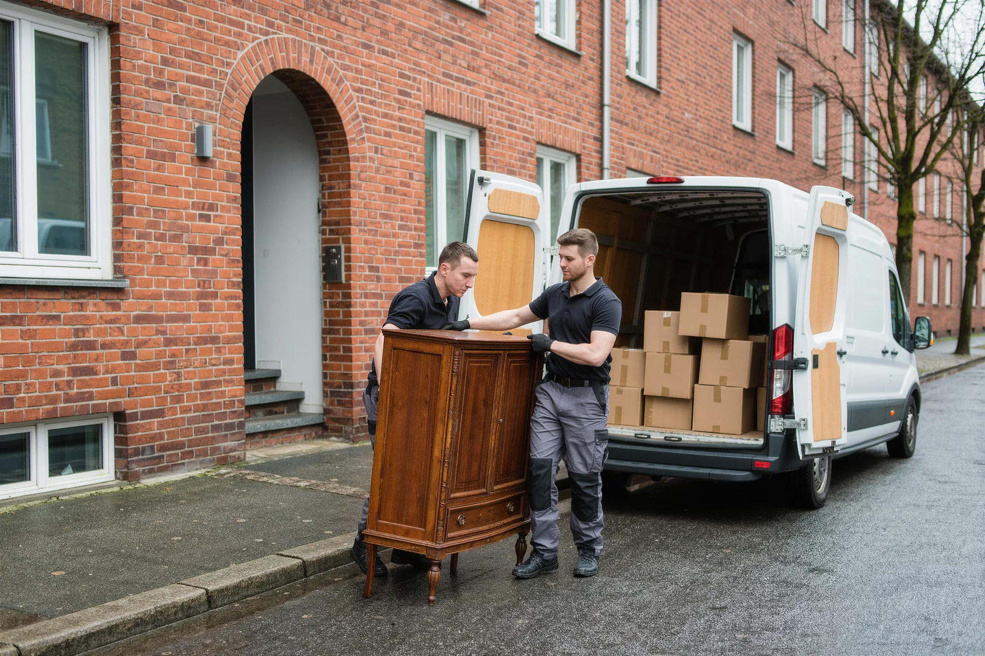 Mitarbeiter tragen einen alten Schrank zum Transporter